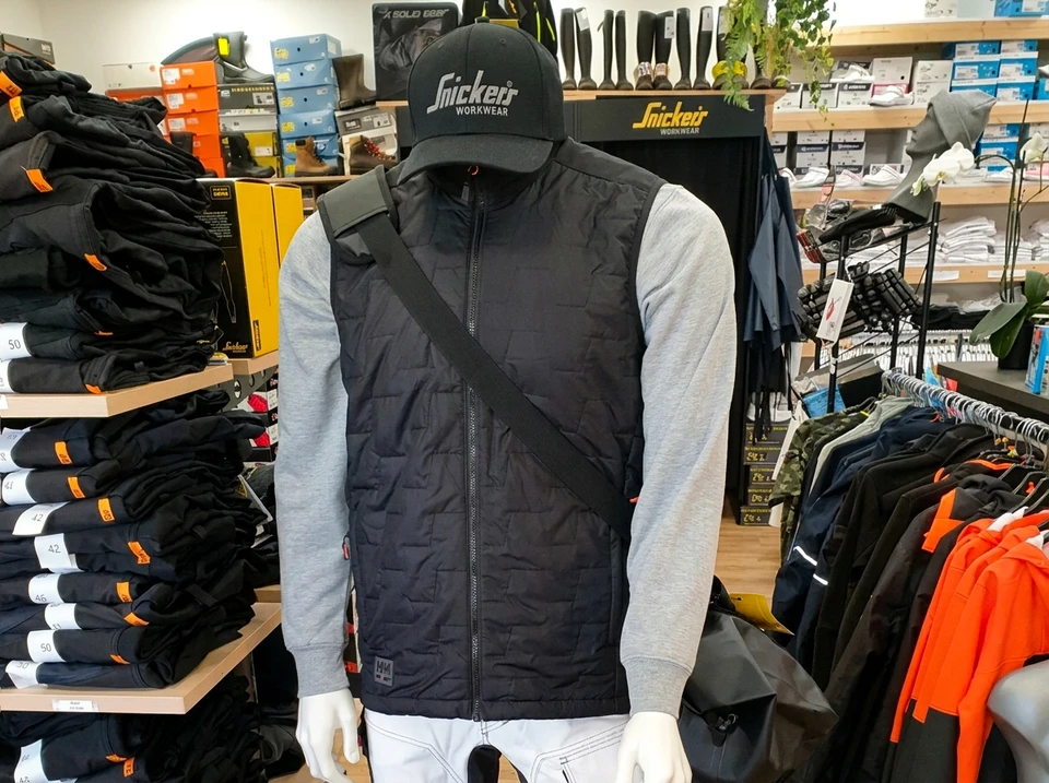 Femme en jean agenouillée chargeant du linge coloré dans un lave-linge blanc à ouverture frontale